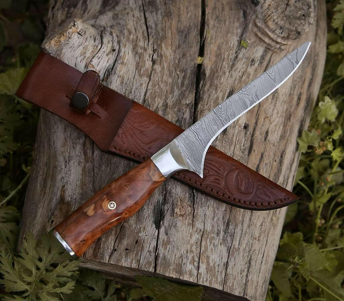 Decorative knife with wooden handle and leather sheath on a wooden surface