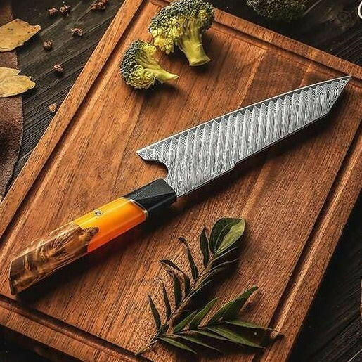 Chef's knife with a decorative handle on a wooden cutting board with broccoli and leaves.