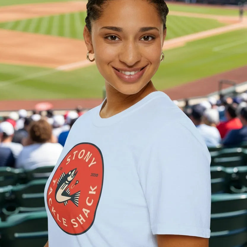 Woman wearing a white t-shirt with a red logo at a baseball stadium