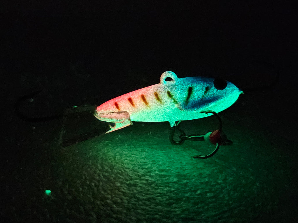 Atomic Bomberz - Rogue Glowing fishing lure on a dark surface