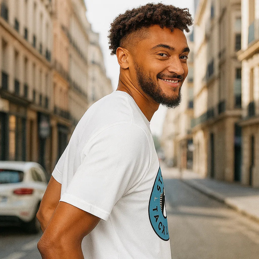 Man wearing a white t-shirt with a blue graphic on a city street