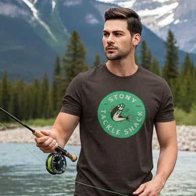 Man wearing a brown t-shirt with a green logo and text fly fishing in a river