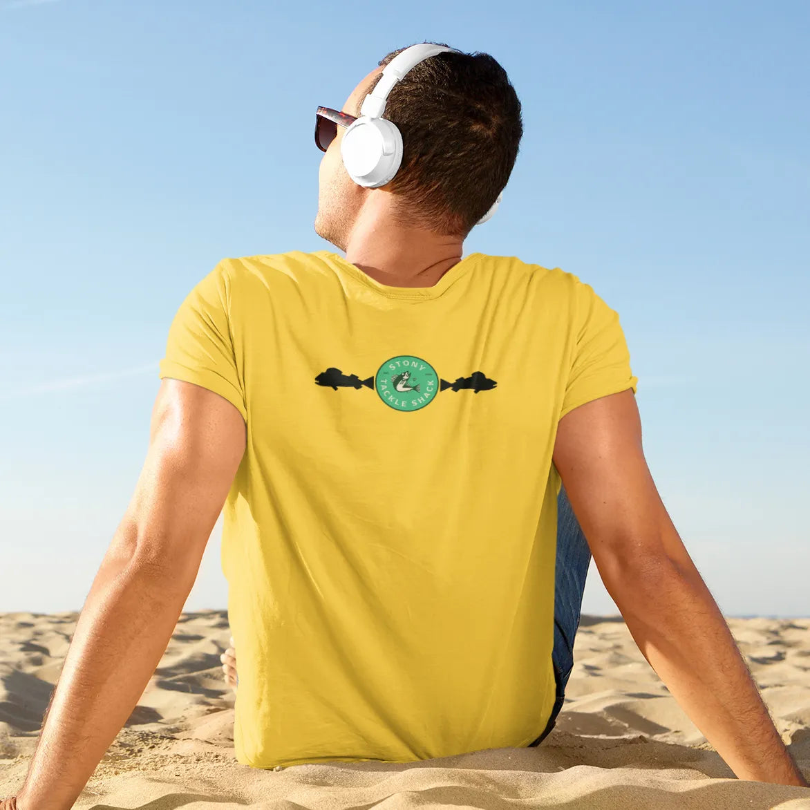 Man wearing a yellow t-shirt with a logo on the beach
