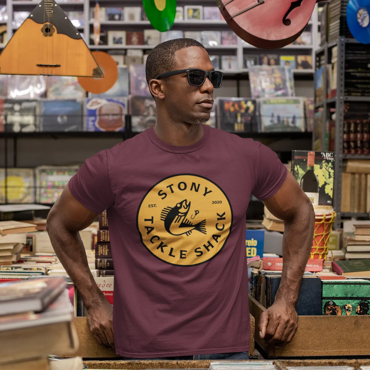 Man wearing a purple t-shirt with a yellow logo in a music store