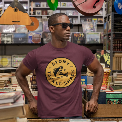 Man wearing a purple t-shirt with a yellow logo in a music store