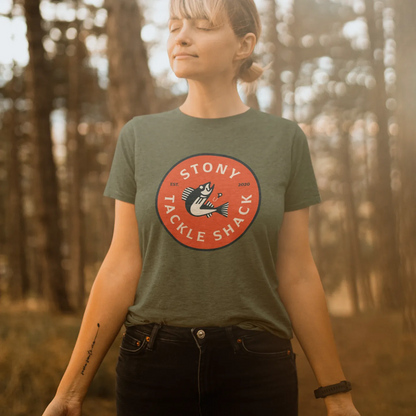 Person wearing a green t-shirt with a red logo in a forest setting