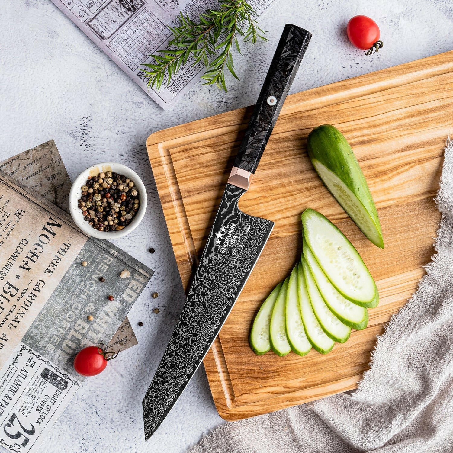 Chef's knife on a wooden cutting board with sliced green apples and peppercorns.