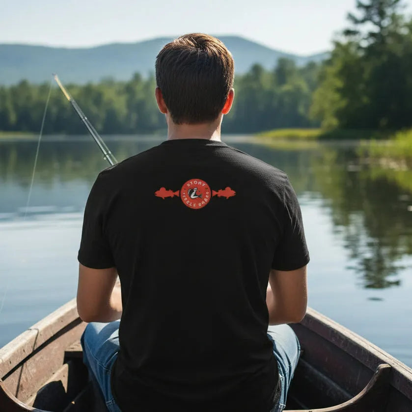 Person fishing from a boat wearing a dark brown shirt with red logo