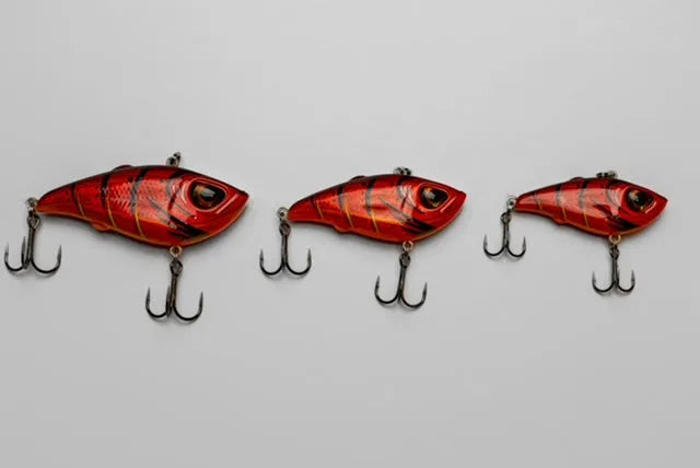 Three red and black fishing lures on a gray background