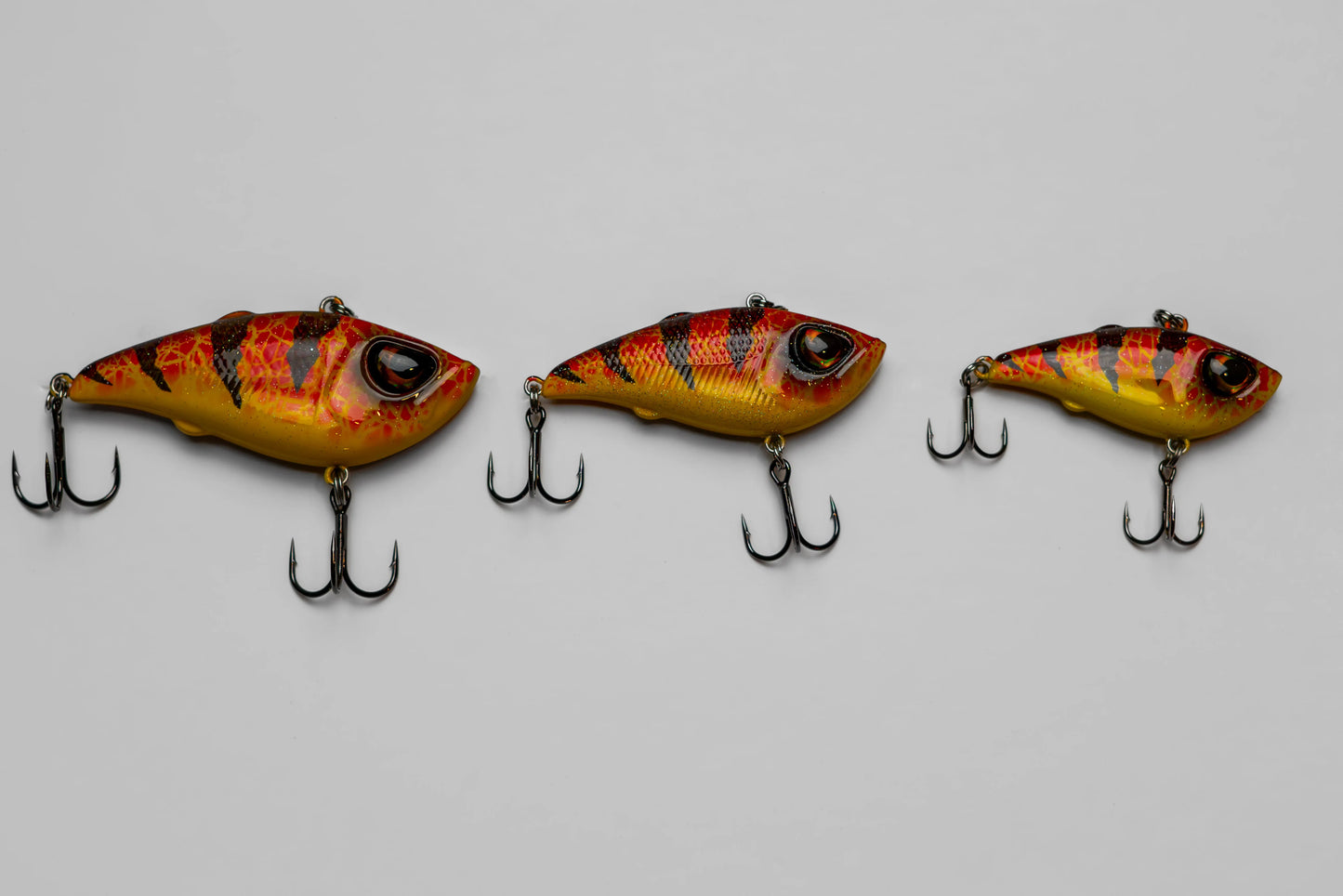 Three fishing lures with a flame-like pattern on a gray background