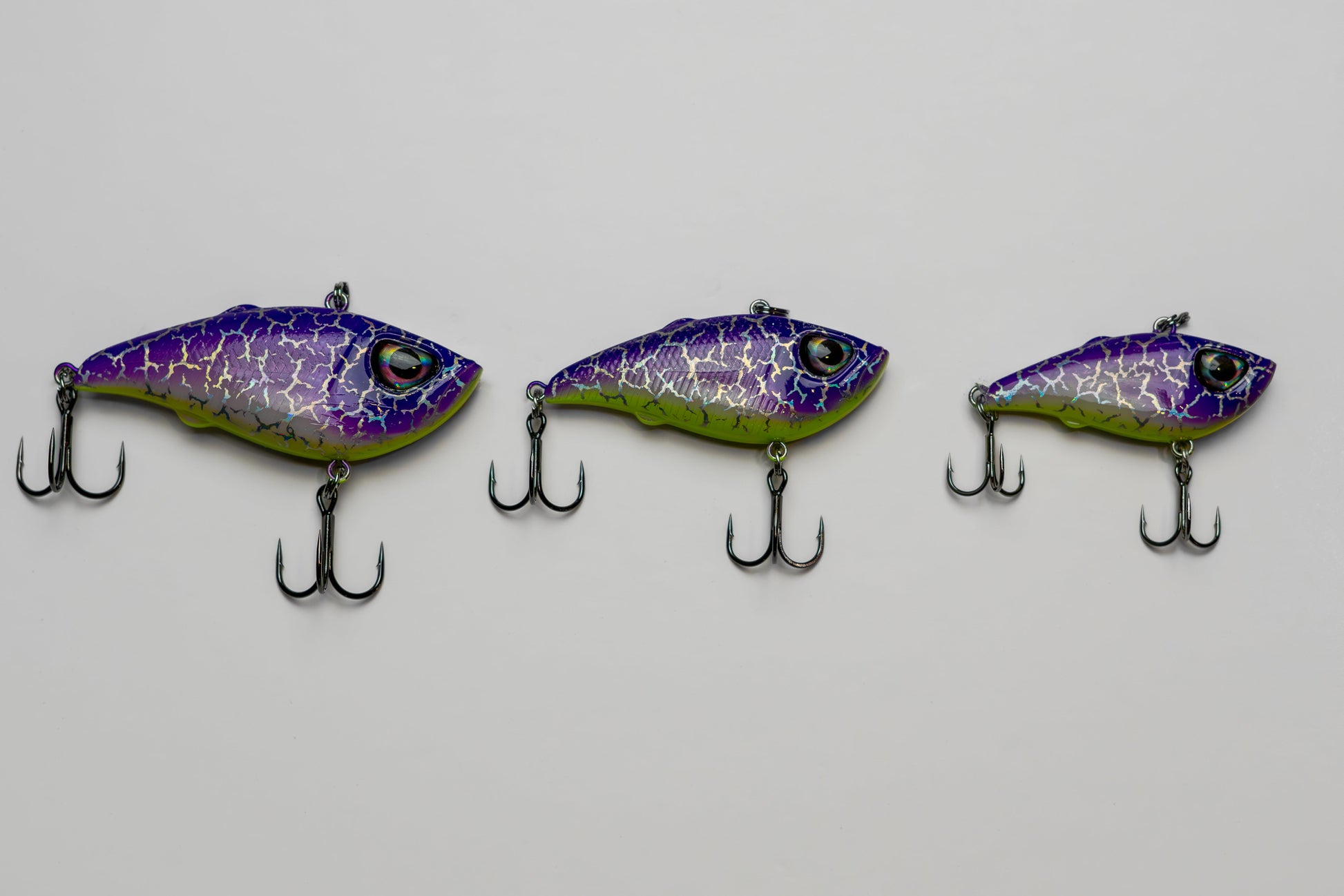 Three purple and green fishing lures on a gray background
