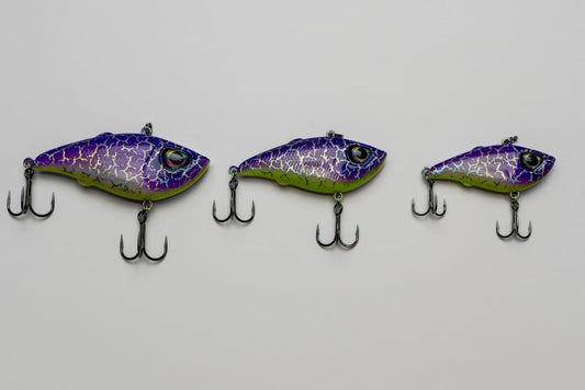Three purple and green fishing lures on a gray background