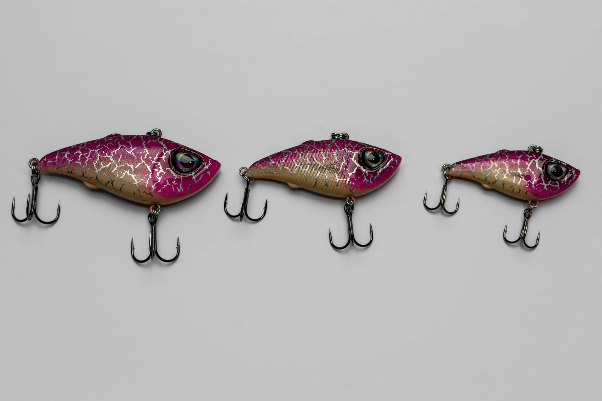 Three pink and purple fishing lures on a gray background
