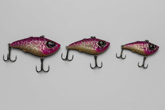 Three pink and purple fishing lures on a gray background