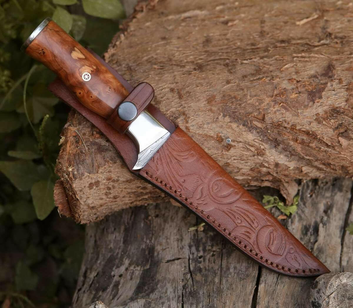 Decorative knife with wooden handle and leather sheath on a wooden log
