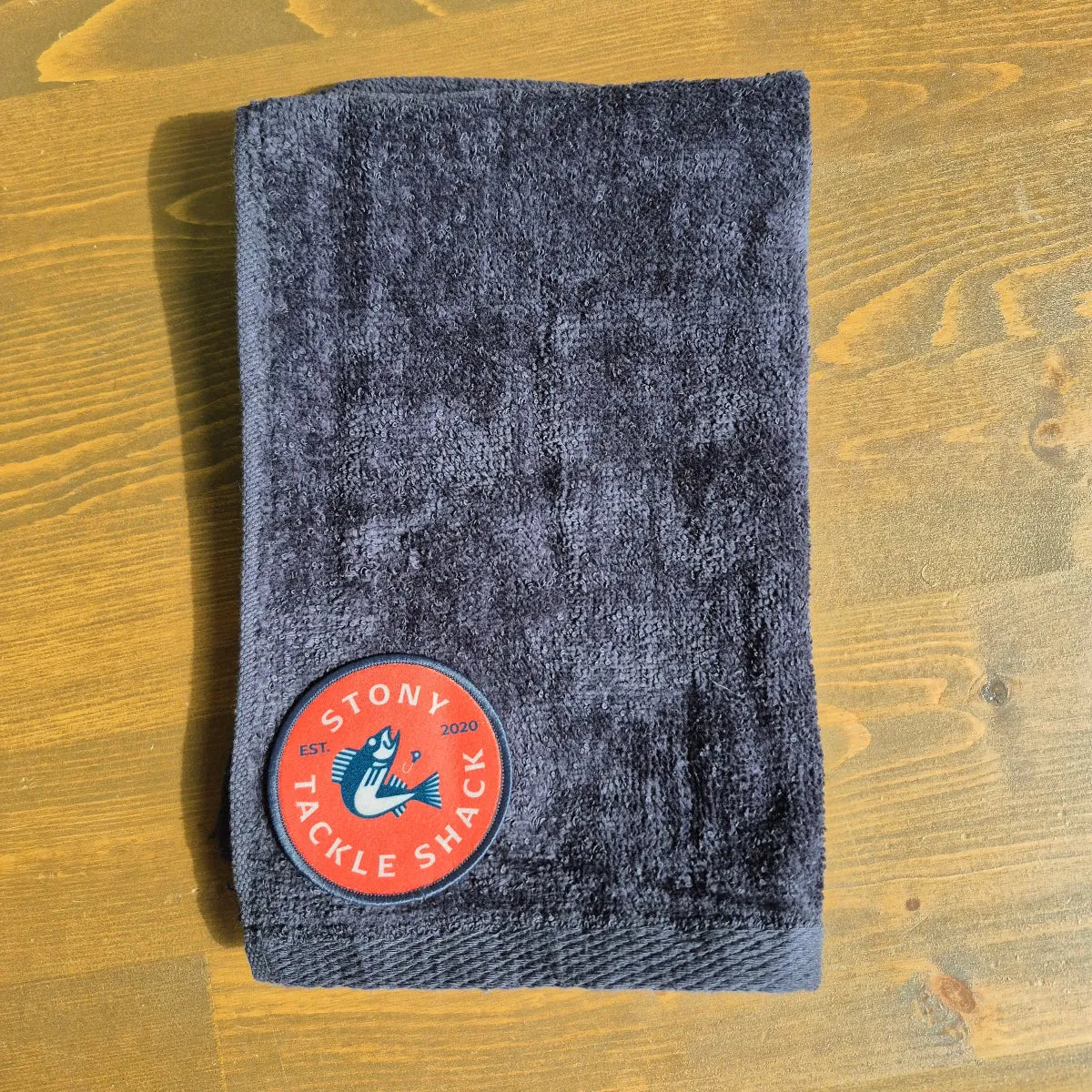 Black hand towel with Red Logo on wood background