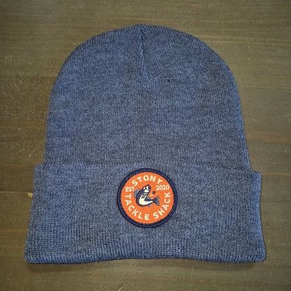 Blue knit beanie with a logo patch on a brown surface