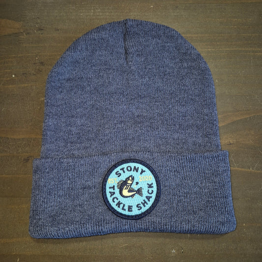 Blue knit beanie with a logo on a wooden surface