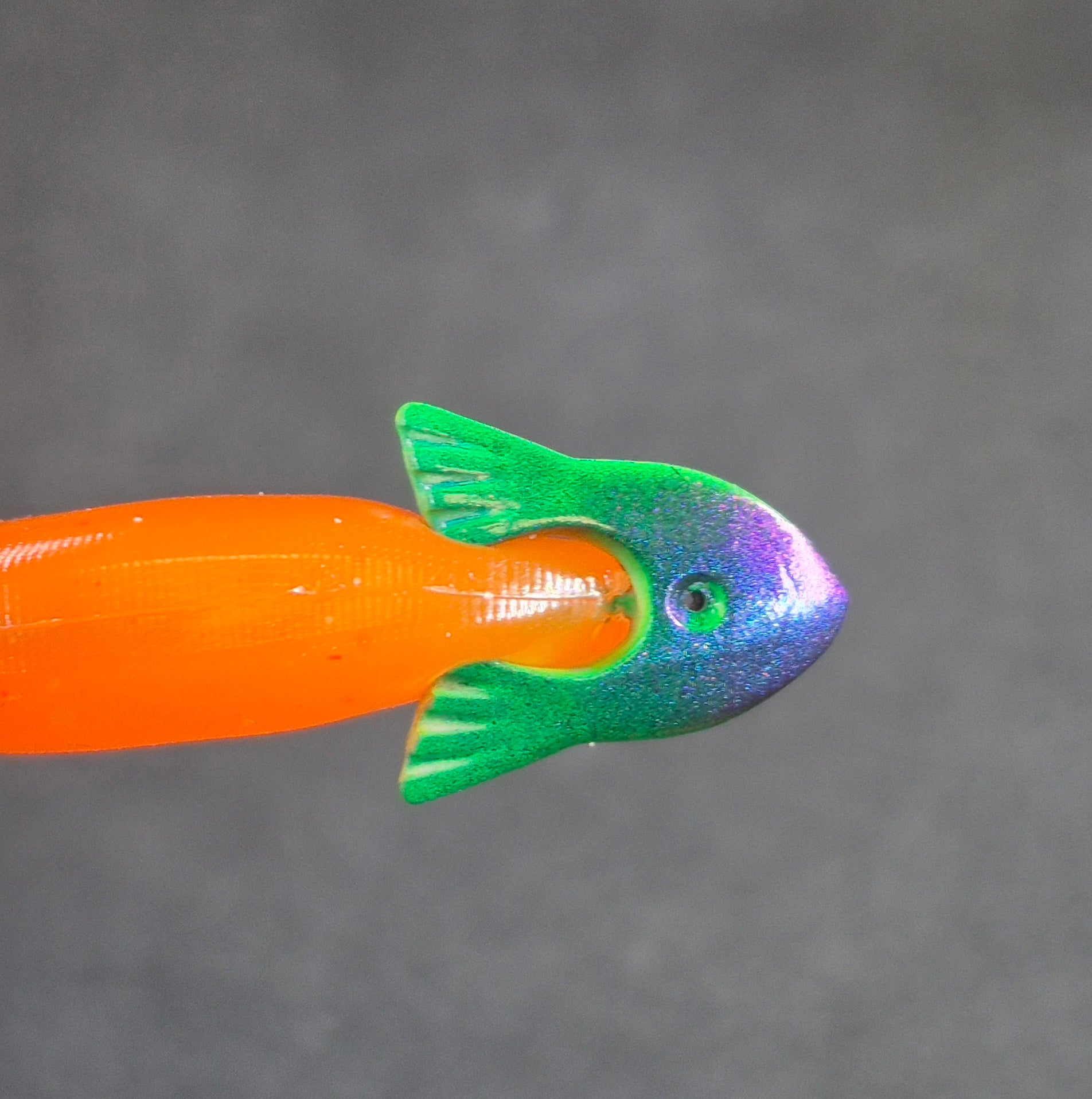 colorful fishing jig head with soft plastic minnow on black background 