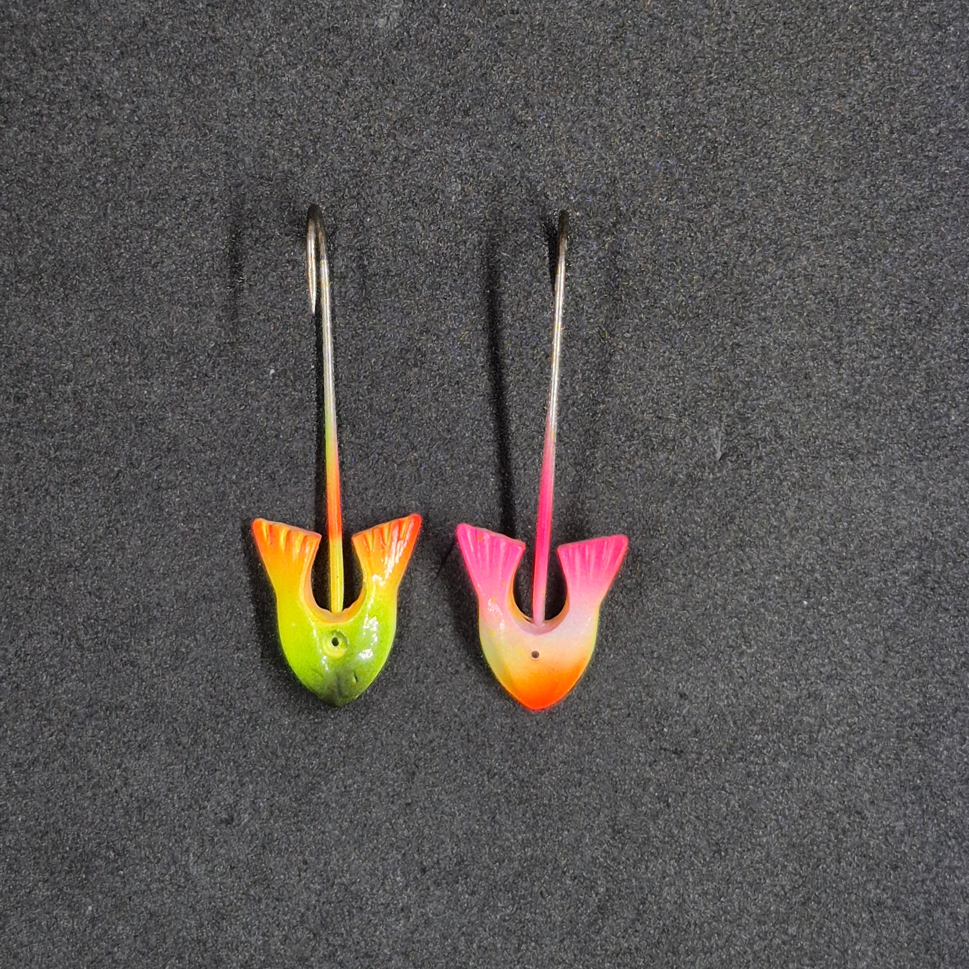 Two colorful fishing lures on a dark surface