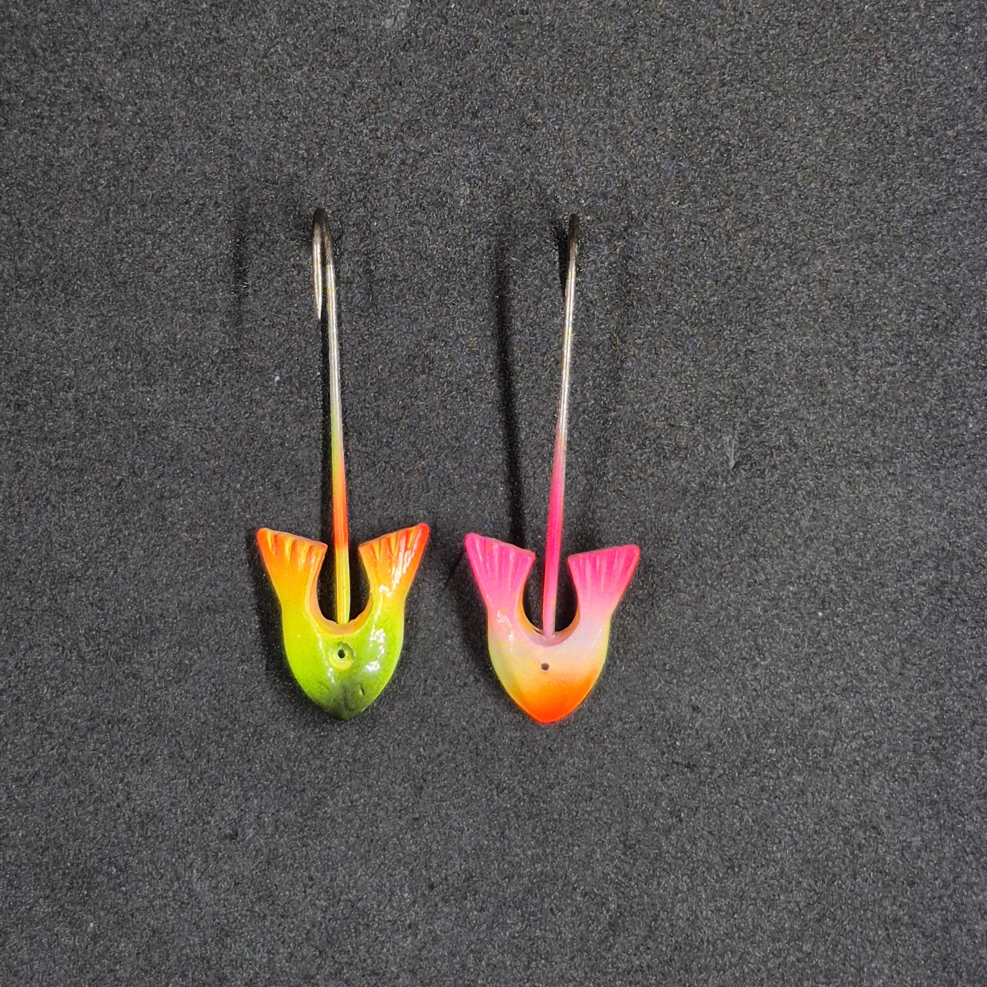Two colorful fishing lures on a dark surface