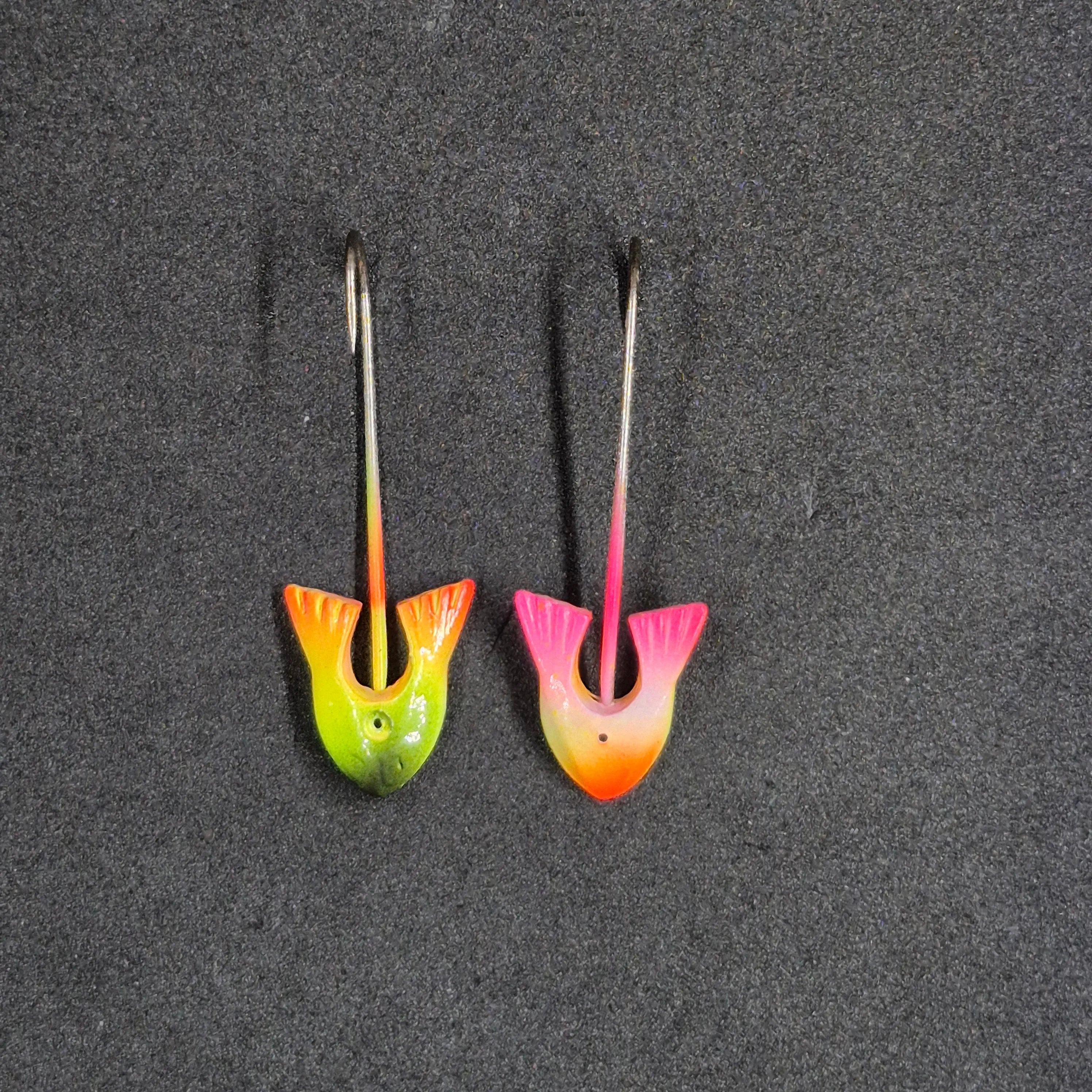 Two colorful fishing lures on a dark surface