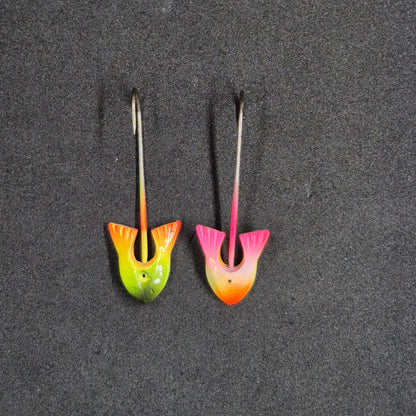 Two colorful fishing lures on a dark surface