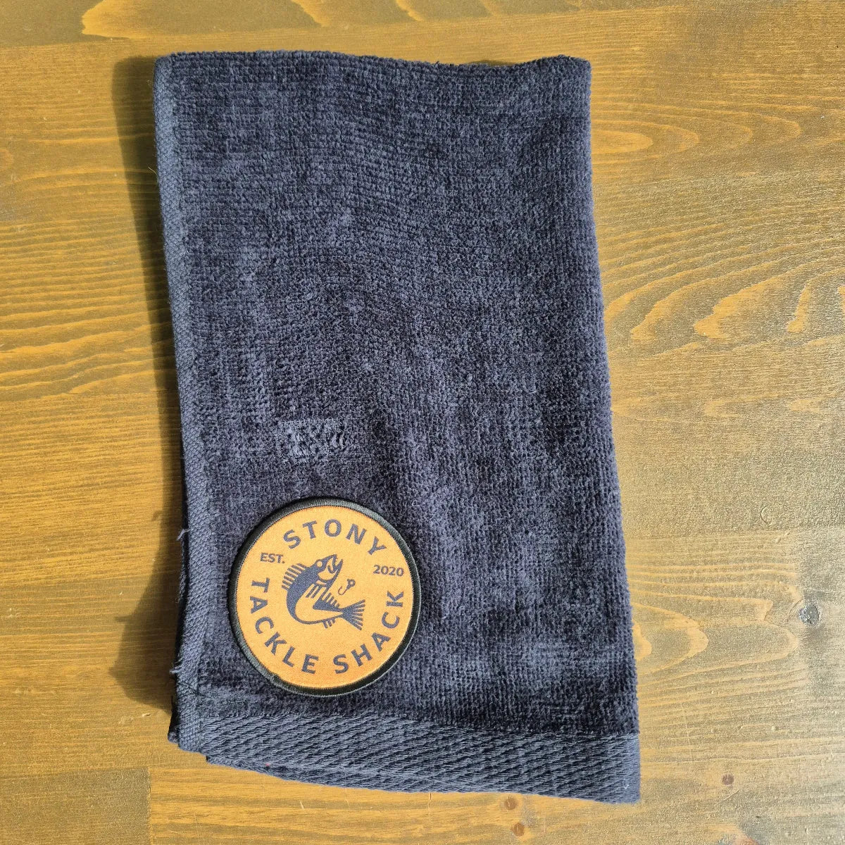 Black hand towel with Yellow Logo on wood background