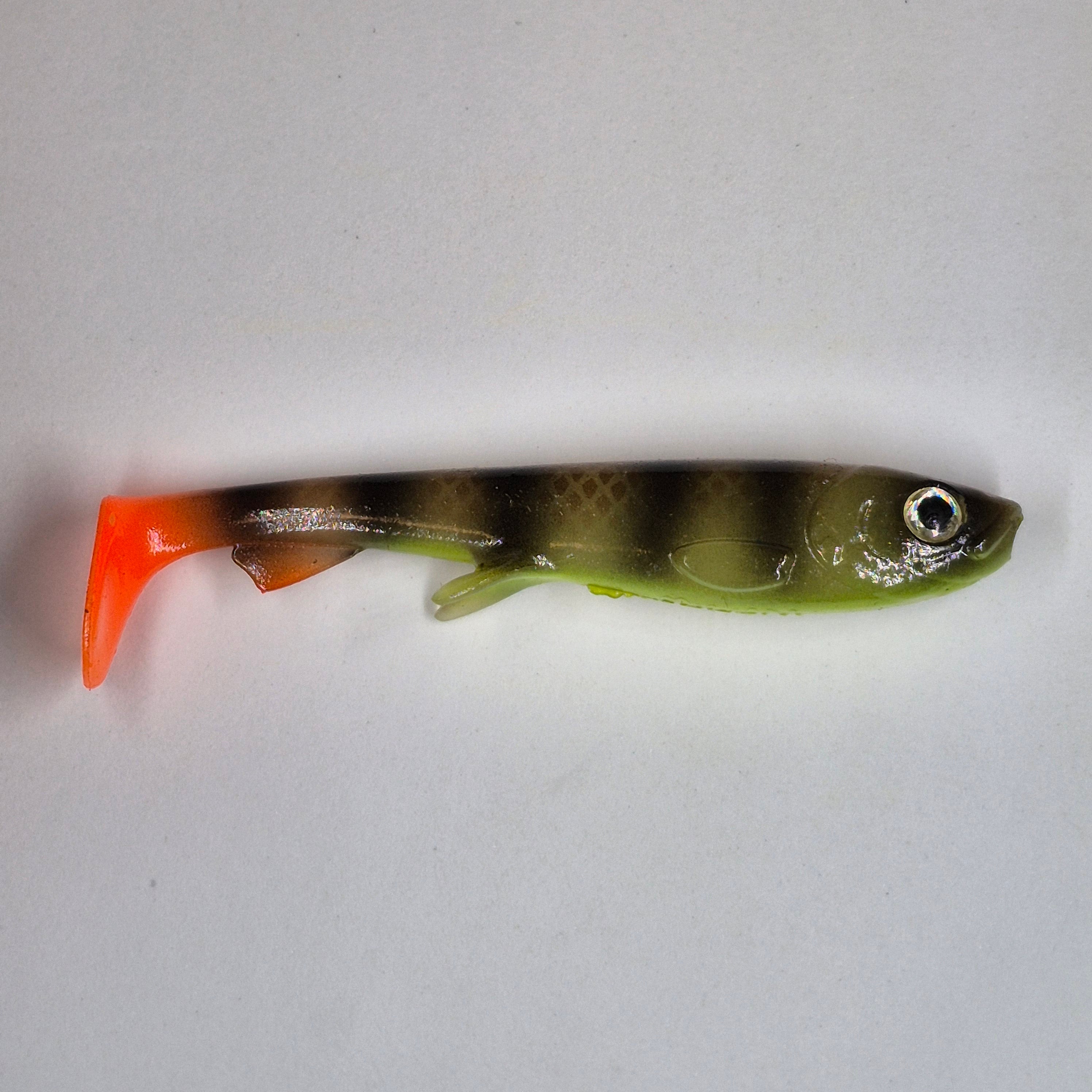 A soft plastic fishing lure shaped like a small fish, featuring a translucent olive-green body with dark vertical stripes, a bright orange tail, and a detailed eye.