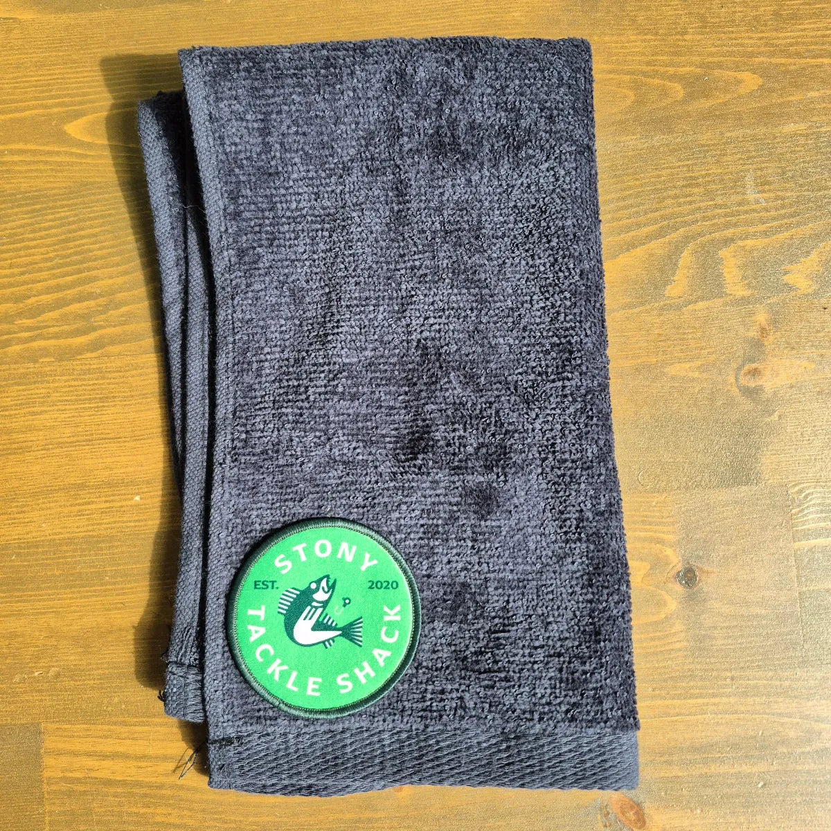Black hand towel with Green Logo on wood background