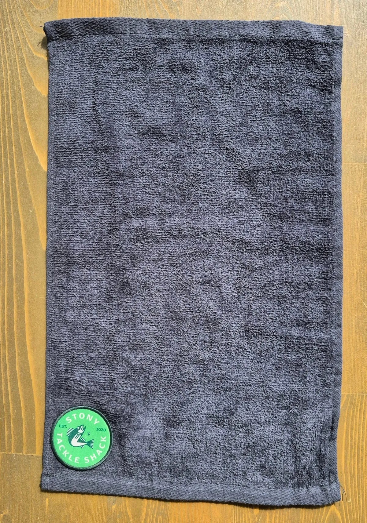 full image of Black hand towel with Green Logo on wood background