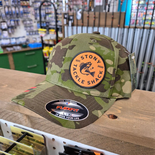 Camouflage hat with Stony Tackle Shack logo on a wooden surface.