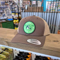 Brown cap with a green logo on a wooden surface in a store setting