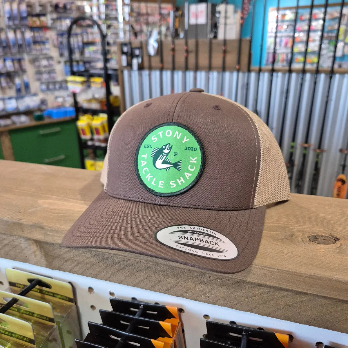 Brown cap with a green logo on a wooden surface in a store setting