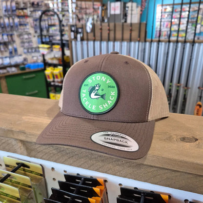 Brown cap with a green logo on a wooden surface in a store setting