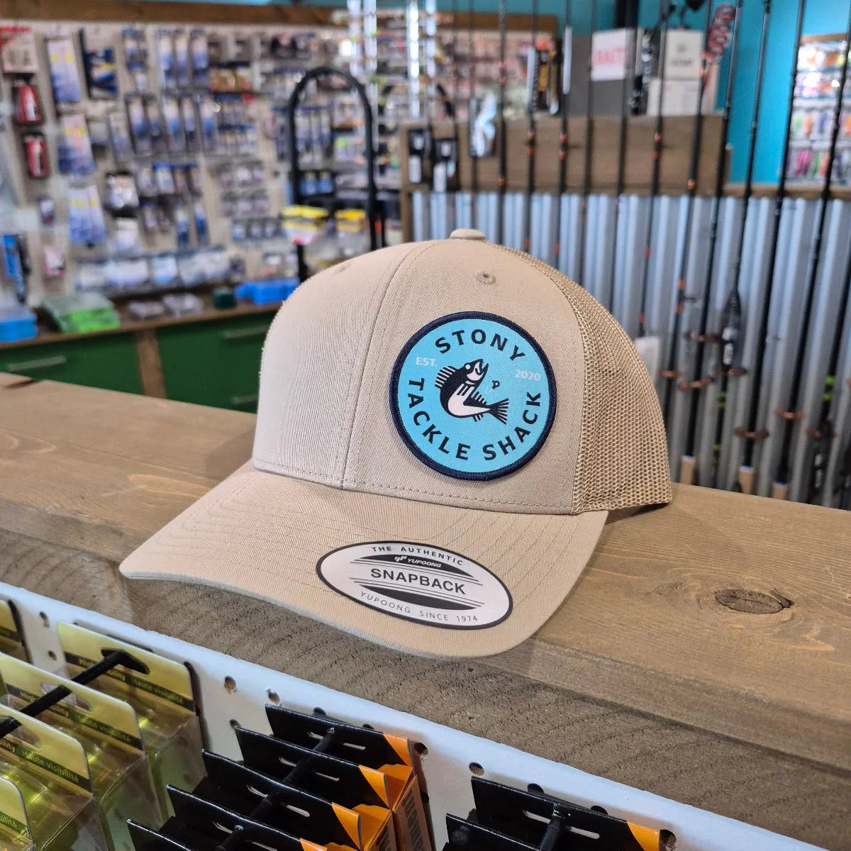 Beige cap with a blue logo on a wooden stand in a store setting