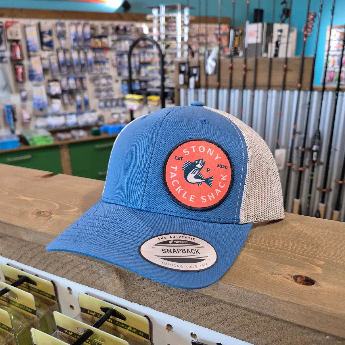 Blue cap with a red logo on a wooden surface in a store setting