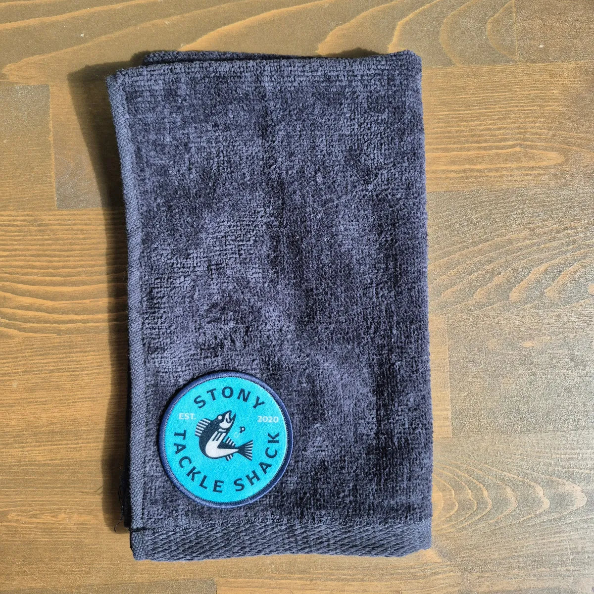 Black hand towel with Blue Logo on wood background