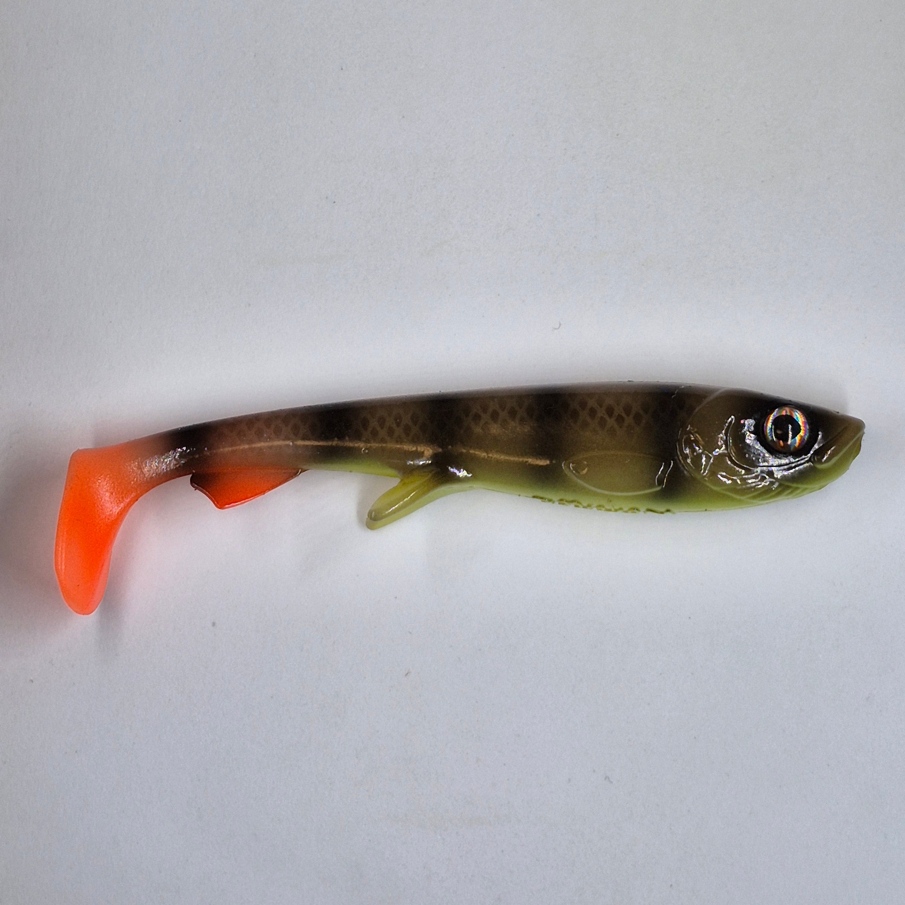 A soft plastic fishing lure shaped like a small fish, featuring a translucent olive-green body with dark brown vertical stripes, a bright orange tail, and a detailed silver-and-black eye.