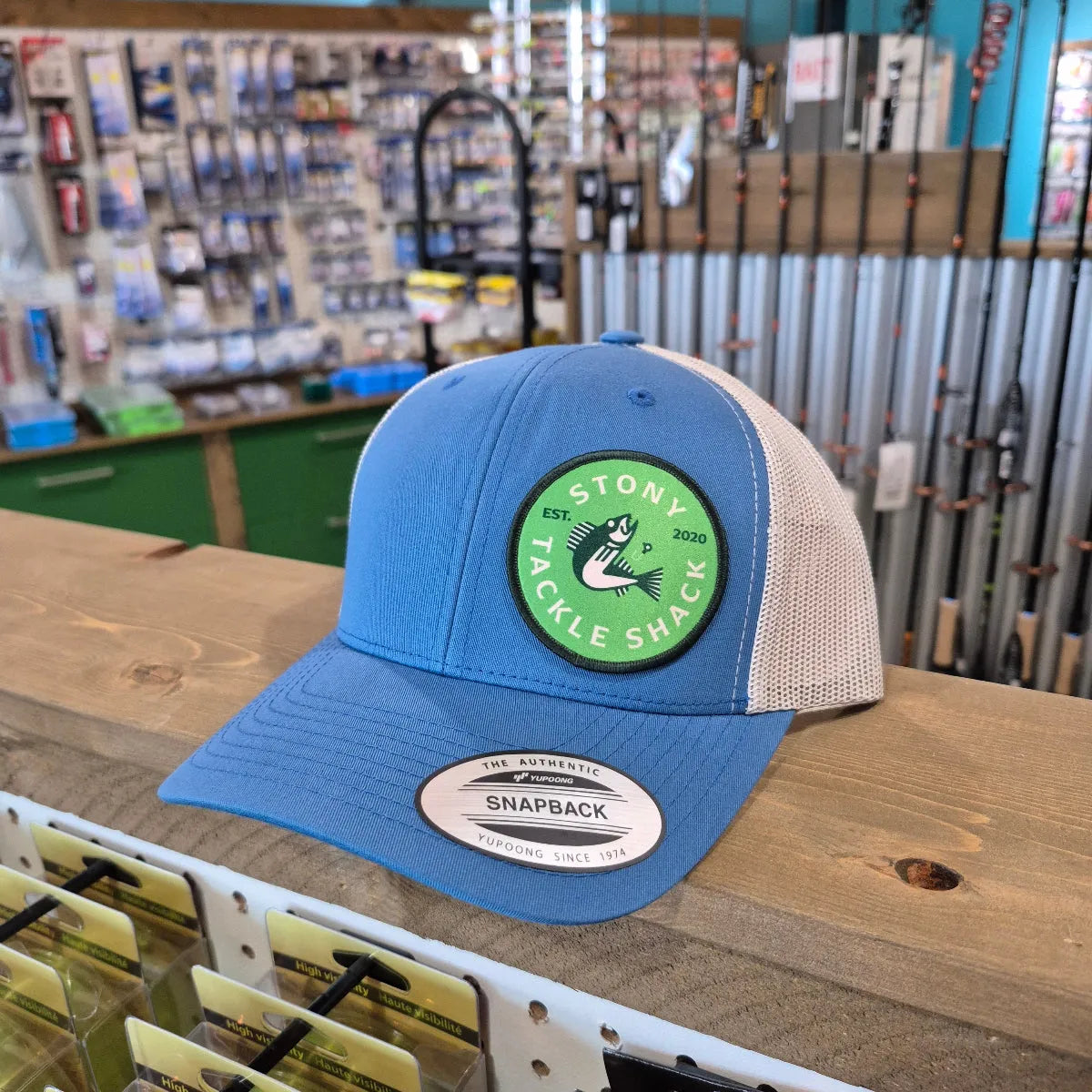 Blue cap with a green logo on a wooden surface in a store setting