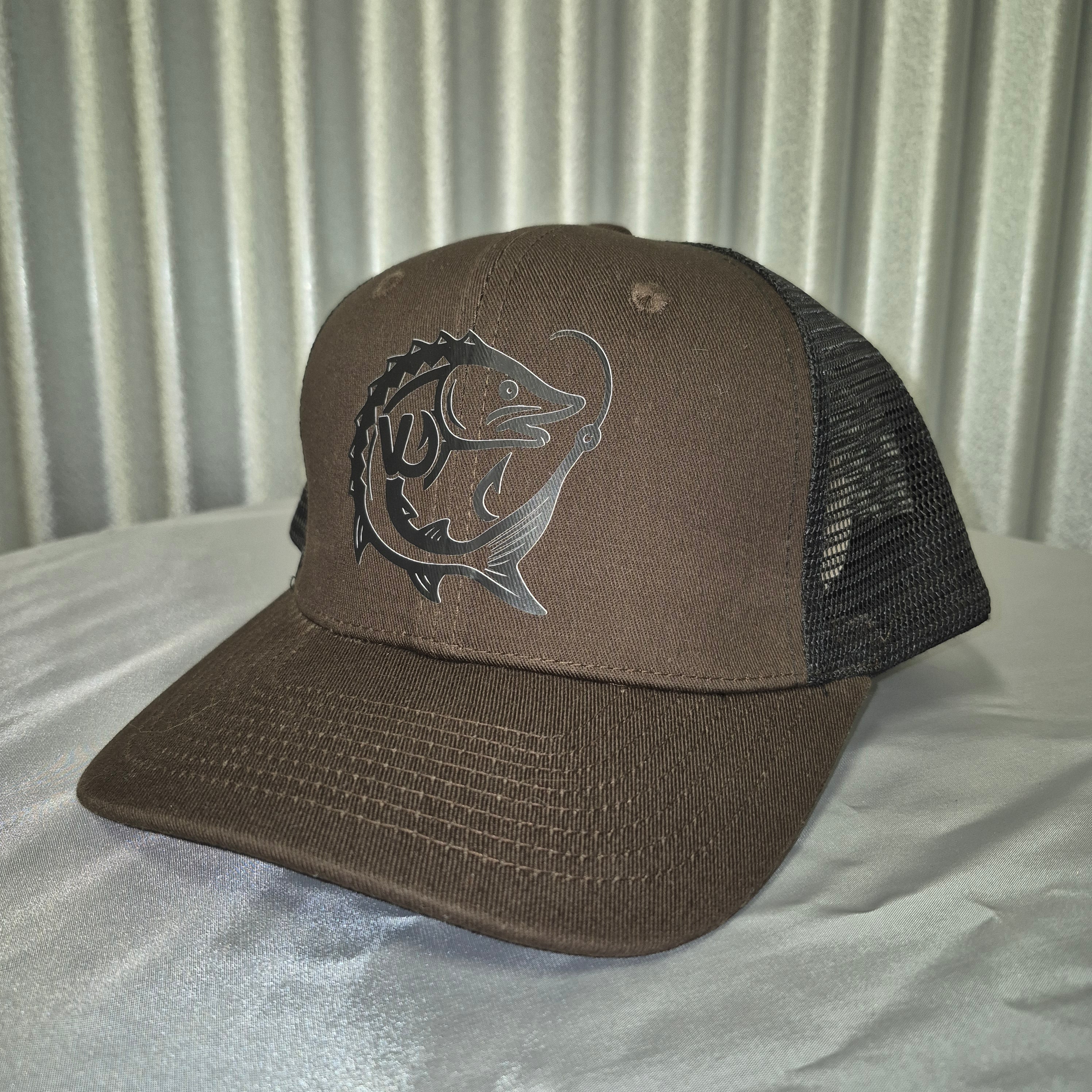 Brown cap with black mesh back and fish logo on a metallic surface