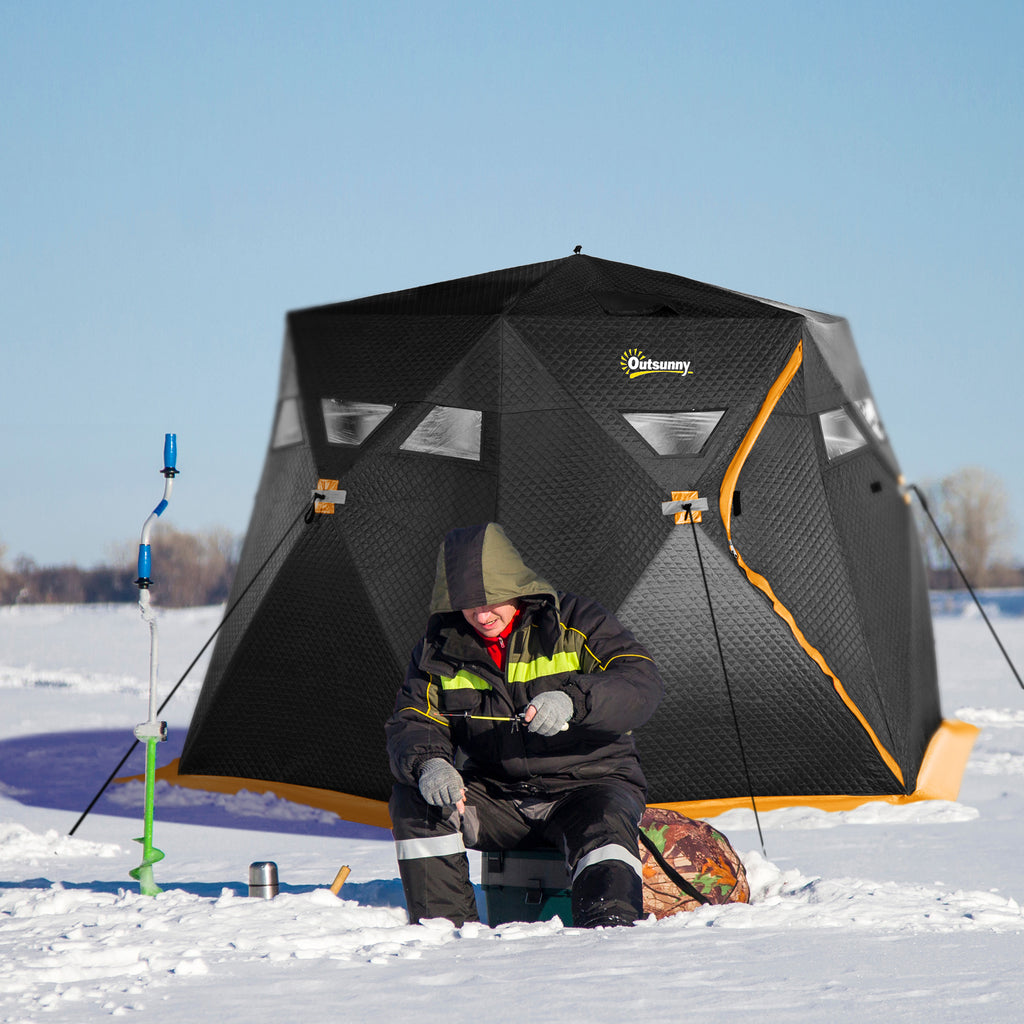 Person ice fishing next to a large black and orange tent on a frozen lake.
